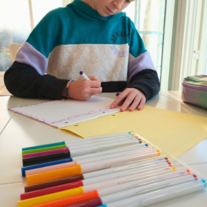 girl sitting at the table writing in her morning journal with markers