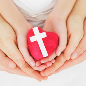 hands of parents and child holding a rock with a cross on it